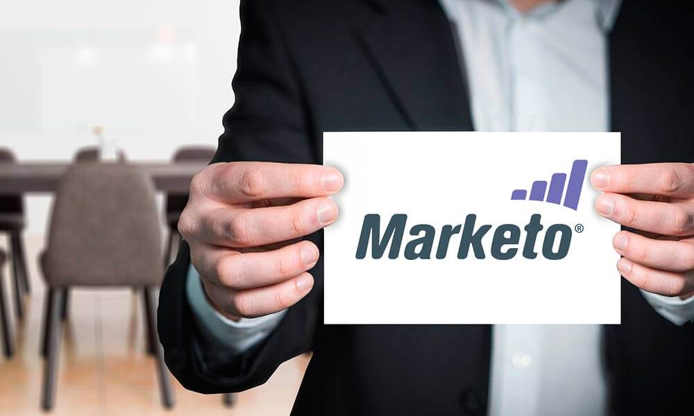 man holding a piece of paper which has Marketo logo on it